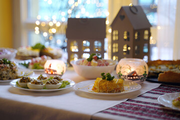 Homemade food on a festive New Year table with focus on mimosa salad.