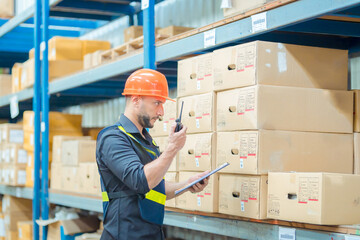Warehouse workers in helmets checking goods and supplies on shelves with goods background in warehouse worker packing in a large warehouse in a large warehouse. Logistics industry concept.
