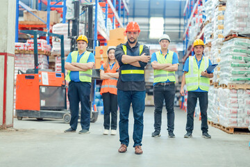 Fototapeta premium Smiling warehouse team with arms crossed in a large warehouse ,Logistics industry concept.