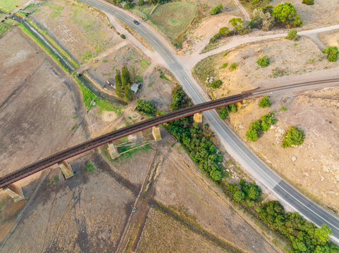 Aerial view of a rail bridge crossing over farmland and winding roads