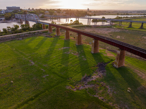 Looking down on a raised railway viaduct over farmland at sunset