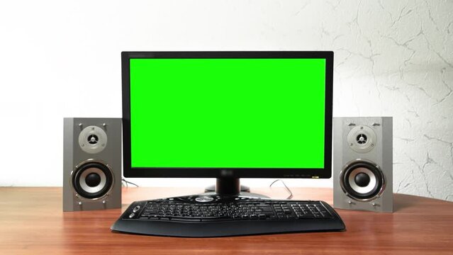 Computer green screen monitor is standing on a desk in an office timelapse hyperlapse forward motion. Design of workplace with audio speakers and black keyboard