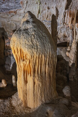 Giant orange stalacmite in the Postojna cave. The white spots is reflected light in water droplets....