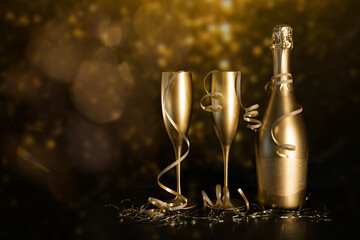 golden champagne bottle and two glasses with ribbons on black bokeh background. new year and...