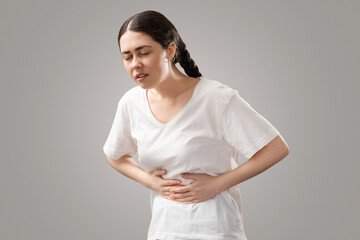 Stomach pain. Suffering young Caucasian woman holds her hands to her stomach. Menstruation and...