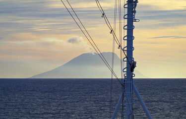 Stromboli volcano at horizon with clouds of smoke coming from summit seen from outdoor deck of...