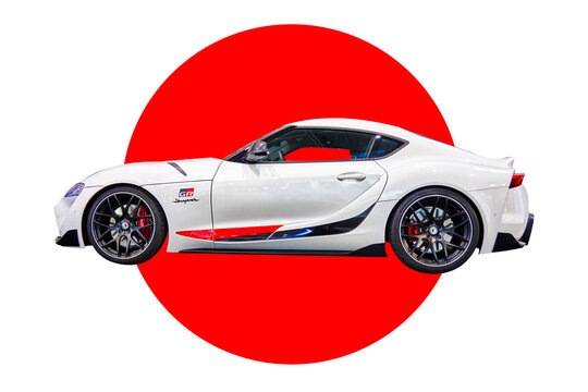 Toyota Supra sports car in white in front of a stylized Japanese flag, Essen, Germany, December 5, 2022