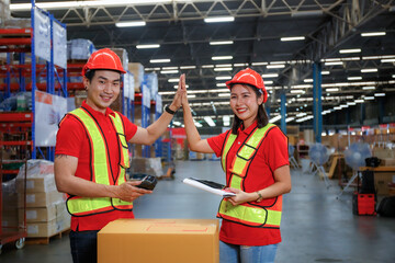 Asian male and female workers in safety suits wear hard hats. Congratulations on completing work inventory check