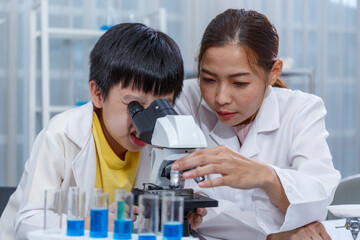 Asian boy and female teacher learn microscopic endoscopic science experiment