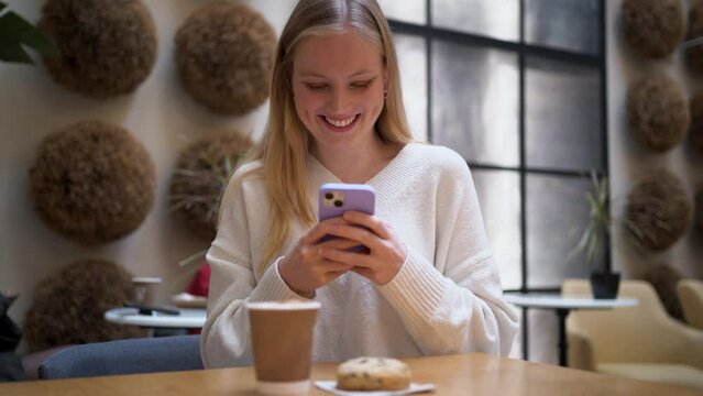 Influencer girl taking a photo of her coffee and chocolate cookie to share it with her followers on social media