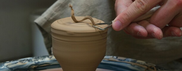 Person working with tools in pottery workshop. European Man sculptor works with clay on a Potter's...