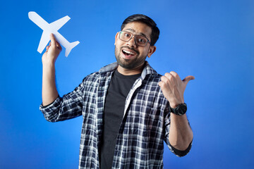 Airplane, vacation, journey. Indian adult student holding paper airplane and pointing with thumb...