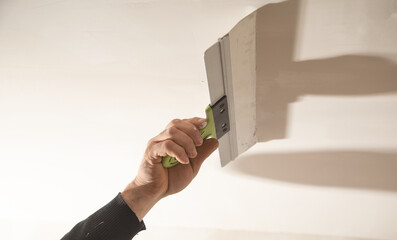Worker is applying putty on a ceiling. Renovating house