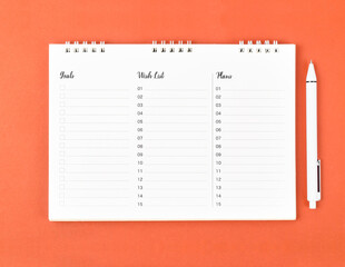 The Blank spiral notebook and white pen on orange colour background for your planning and note text.