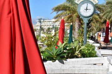 海辺のテラスの時計と赤いパラソル