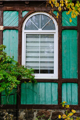 Fototapeta na wymiar Arched plastic window in old wooden house green color.