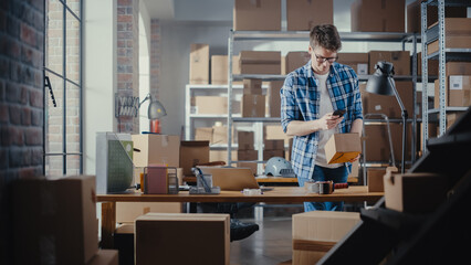 Inventory Manager Using Smartphone to Scan a Barcode on Parcel, Preparing a Small Cardboard Box for Postage. Young Small Business Owner Working on Laptop in Warehouse with Colleague.
