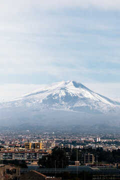 Snowy volcano near city on cloudy day