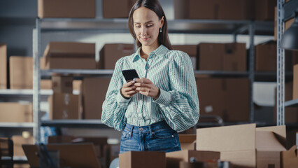 Portrait of a Beautiful Small Business Owner Using Smartphone at Work in a Warehouse. Female...