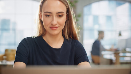 Close Up Portrait of a Beautiful Manager Working in Creative Agency, Writing Corporate Marketing Strategy Plan on Laptop Computer. Creative Specialist Smiling, Happy With Her Work in a Startup.