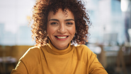 Portrait of an Attractive Arab Female in Creative Agency. Young Stylish Manager with Curly Hair Smiling, Looking at Camera. Manager Working in Modern Company. - obrazy, fototapety, plakaty