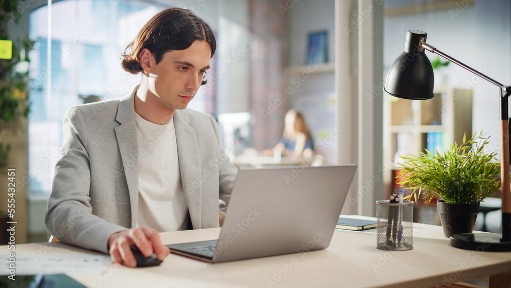 Poster stylish male employee in gray casual jacket working on laptop in office during daytime. close up on 