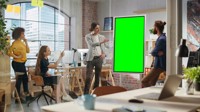 Stylish Young Project Manager Talking on a Team Meeting in Creative Agency Conference Room. Colleague Showing Business Plan Presentation on Green Screen Mock Up Chroma Key Monitor.