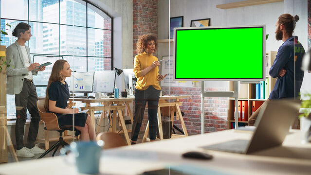 Positive Businesswoman Leading a Team Meeting in Creative Office Conference Room. Excited Multiethnic Woman Showing Presentation on Green Screen Mock Up Chroma Key Monitor. - Powered by Adobe
