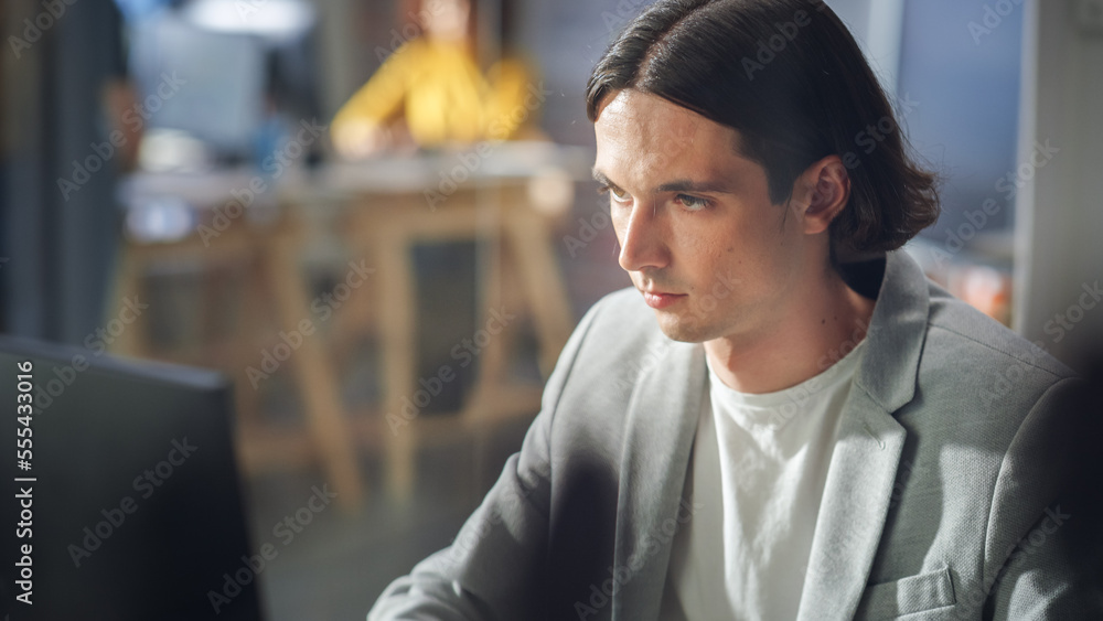Poster close up portrait of a handsome manager sitting at a desk in creative office. young stylish man in a