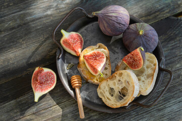 Sandwiches with ricotta, fresh figs, walnuts and honey on rustic wooden board over black backdrop, top view