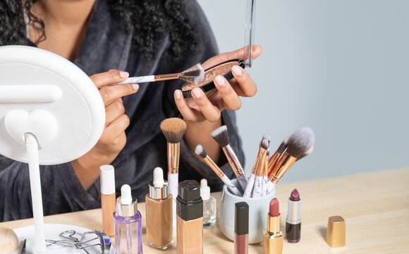 Crop woman picking makeup product on brush