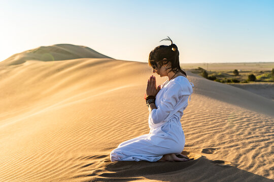 Woman gesticulating namaste in desert
