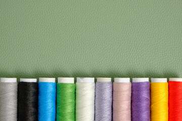 Reels with multi colored sewing threads green background.