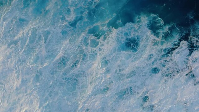 Top down aerial drone view of abstract ocean wave textures crashing in slow motion