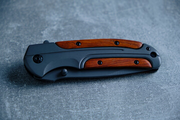Tactical folding knife for survival on concrete background.