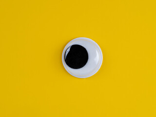 single wobbly googly eye isolated on a yellow background with copyspace business logo