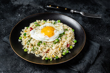 Fried rice with chicken, egg and vegetables in a plate. Black background. Top view