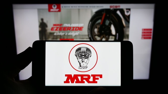 Stuttgart, Germany - 12-11-2022: Person holding smartphone with logo of Indian company Madras Rubber Factory (MRF Tyres) on screen in front of website. Focus on phone display.