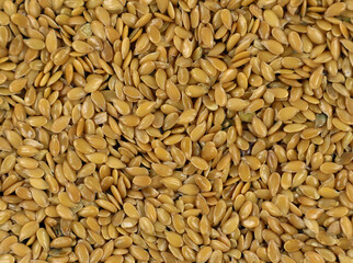 Texture of flax golden seeds close-up, yellow brown seeds background close up