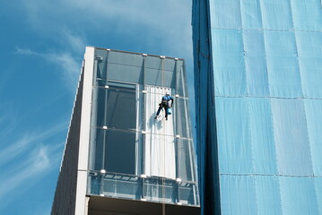 高層ビルの窓ガラスを磨く清掃員 - obrazy, fototapety, plakaty