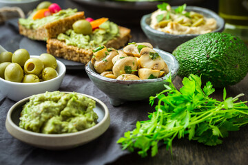 Vegan raw food snacks with fresh juicy vegetables, avocado dip and humus