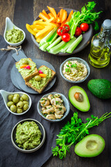 Vegan raw food snacks with fresh juicy vegetables, avocado dip and humus