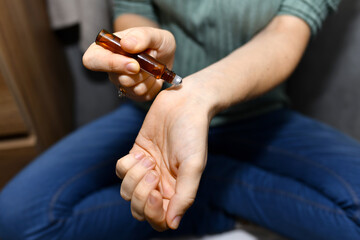 woman applying essential oils on her wrist at home. personal skin care