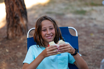 Little girl with sandwich on a camping day.