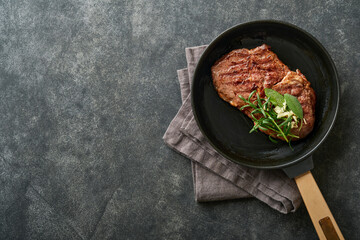 Steaks. Sliced grilled meat steak New York or Ribeye with spices rosemary and pepper in iron pan black on marble board on old wooden background. Top view. Mock up.