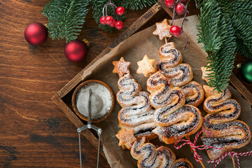 Obraz na płótnie Canvas Christmas tree shape puff pastry cakes with chocolate filling, sugar powder and lollipops on old wooden background. Christmas, New Year Appetizer. Festive idea for Christmas or New Year dinner.