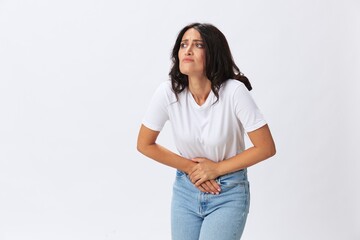 Woman pain during menstruation, abdominal pain appendicitis, age problems, early menopause, cystitis, a woman in a white t-shirt on a white background in jeans, copy space