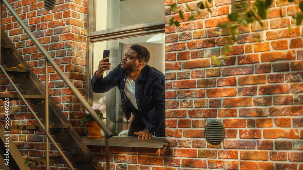 Poster Distressed Young Black Man Doesn't Understand Why There is No Cellular Connection on His Smartphone, Frantically Reaching Out to the Sky with a Mobile Phone from His Apartment Window.