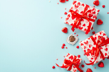 Valentine's Day concept. Top view photo of gift boxes heart shaped chocolate candies and sprinkles on isolated pastel blue background with copyspace