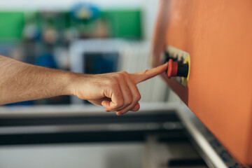 Mans hand presses the button to start a machine